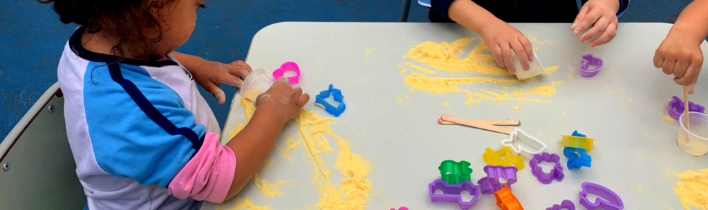 mãos de crianças fazendo arte na educação infantil com amido de milho.