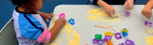 mãos de crianças fazendo arte na educação infantil com amido de milho.